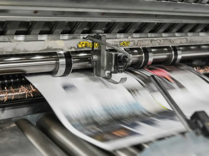 Eine laufende Rotationsmaschine, bedruckte Bogen laufen unter den Walzen durch